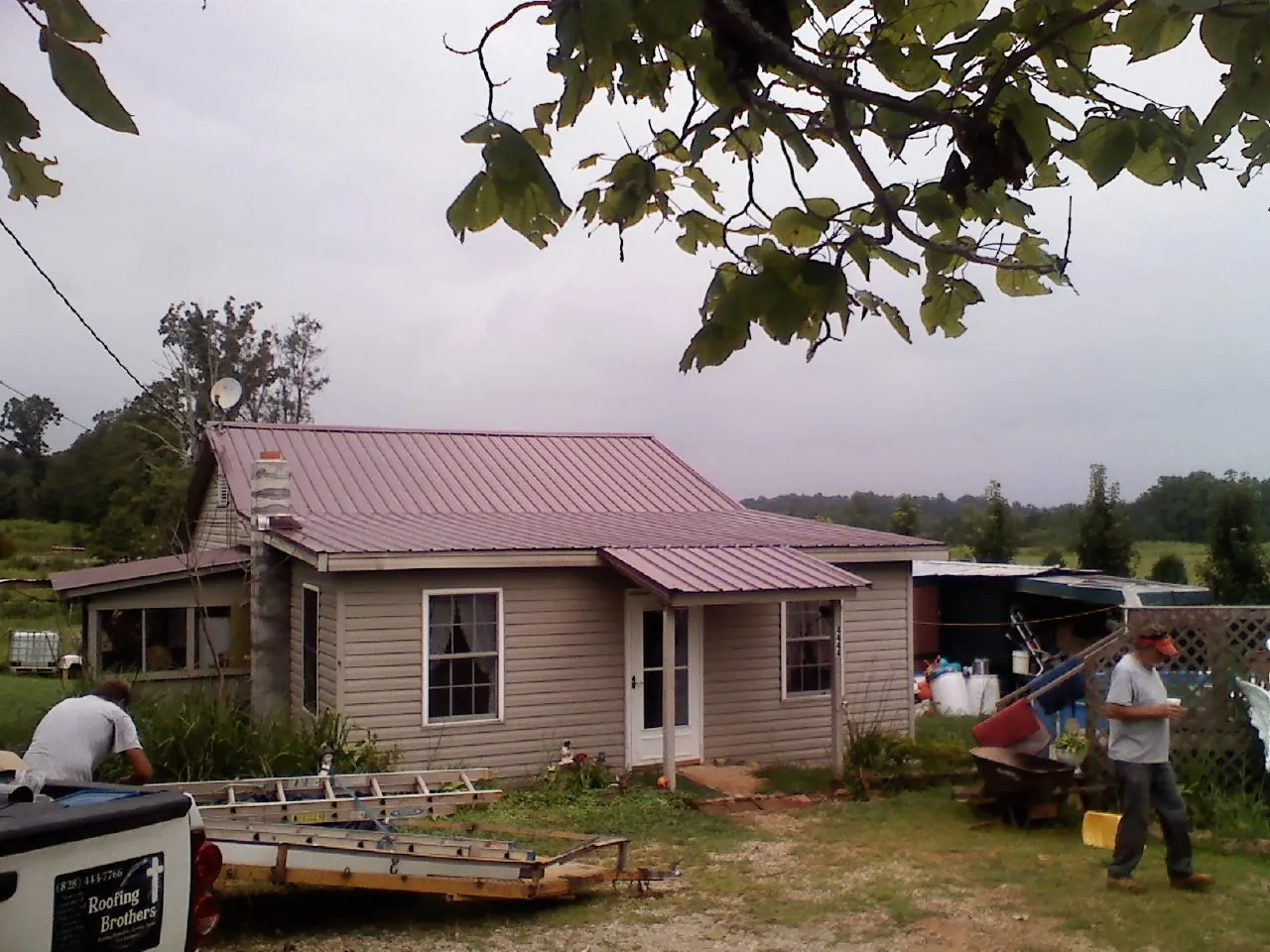 Crew finishing a mauve metal roof on a small farmhouse in Crystal Spring