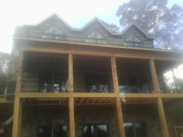 Dormers and porch framing on a large log home under construction — Roof Coating work by our crew in Crystal Spring