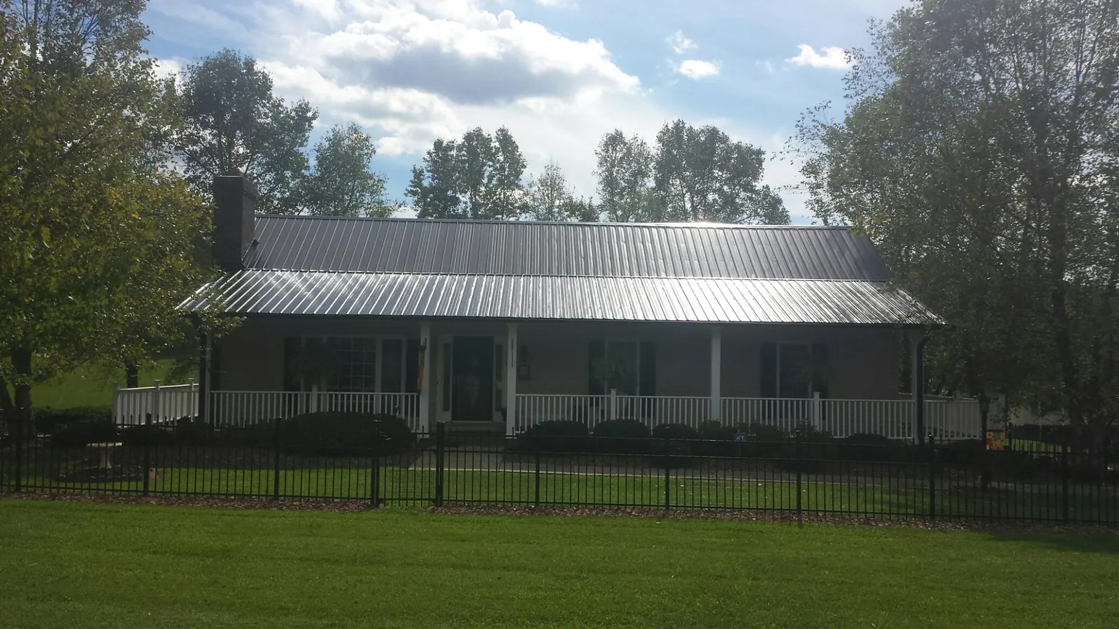 Gray metal roof on a brick ranch with a full width front porch — Gutter Guard Installation work by our crew in Crystal Spring