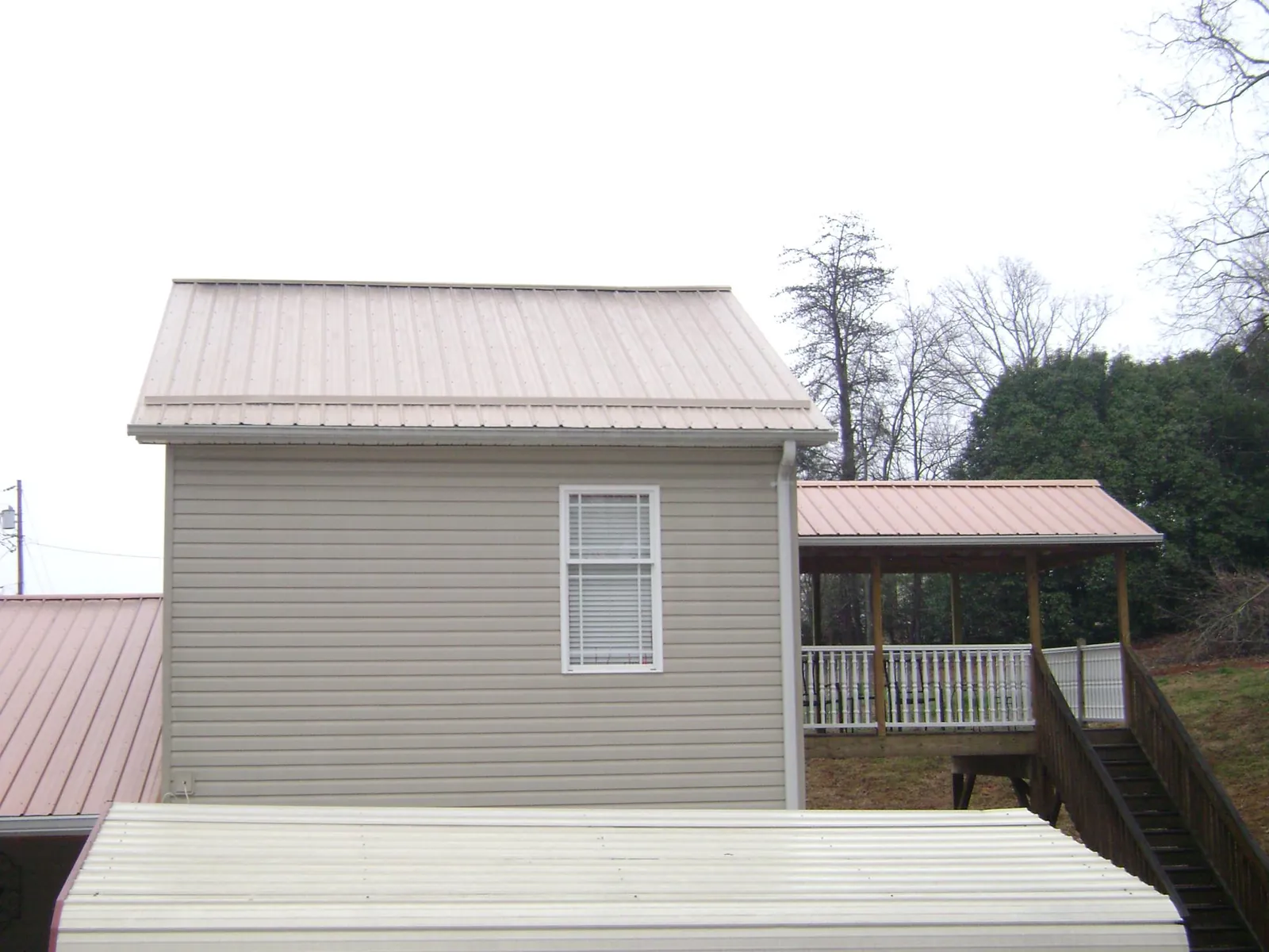 Tan metal roofs on a two story addition and attached porch, from a Roof Replacement job in Crystal Spring