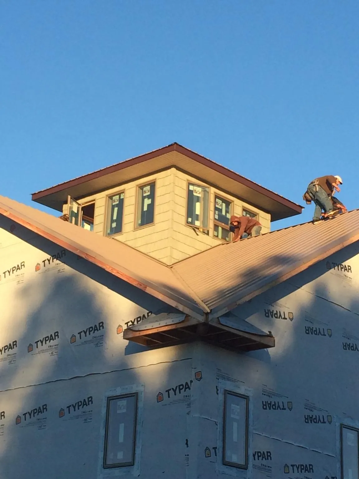 Roofers working around a rooftop cupola on a new metal roof at sunset — Roof Waterproofing in Crystal Spring by Roofing Brothers